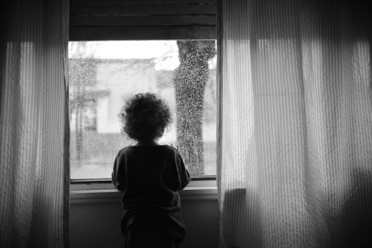 criança com trauma infantil olhando pela janela