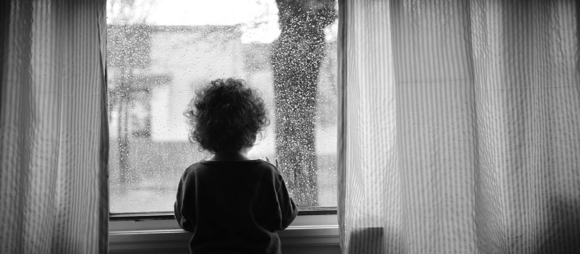 criança com trauma infantil olhando pela janela